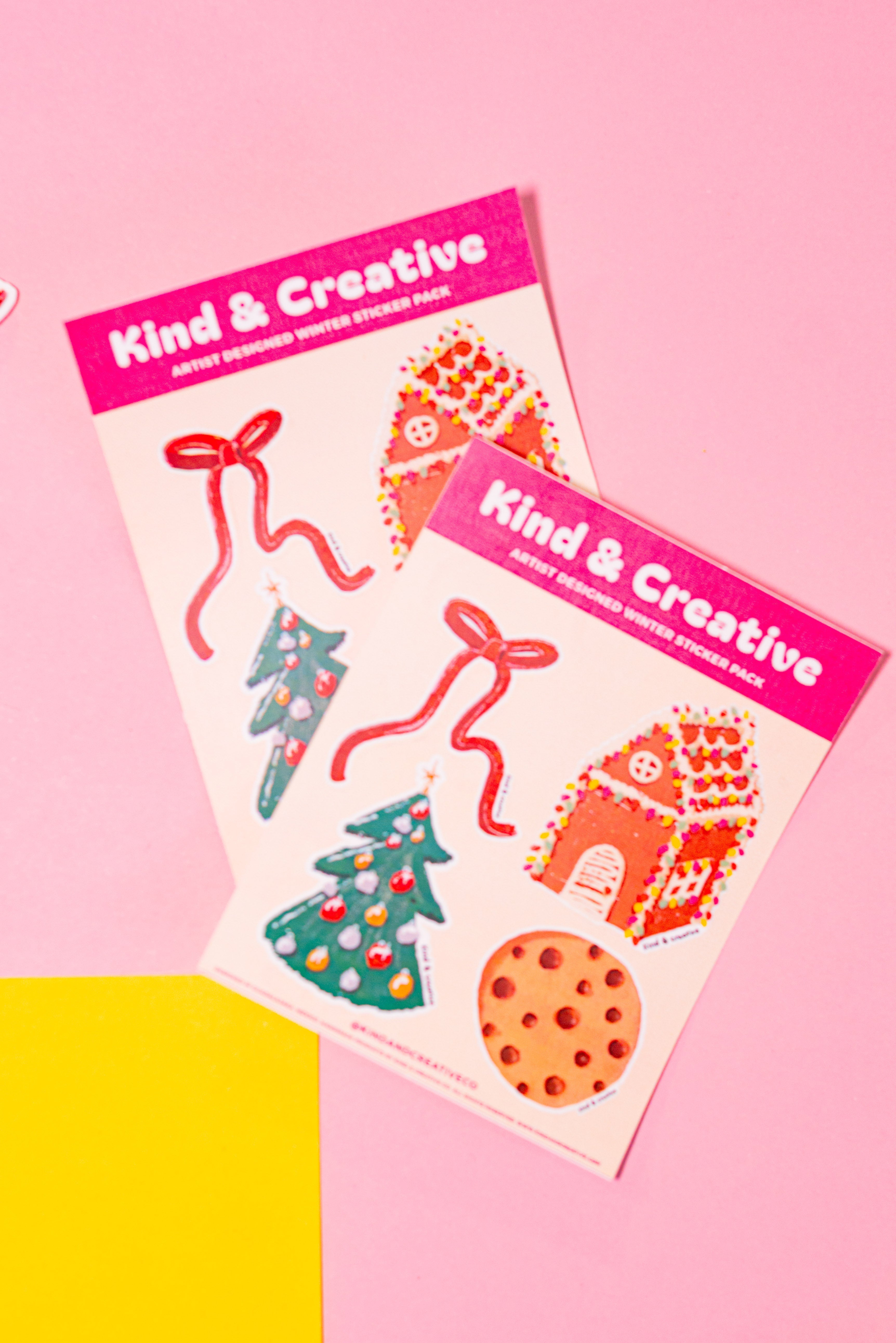 Sticker sheets with festive designs and 'Kind & Creative' branding on a pink background